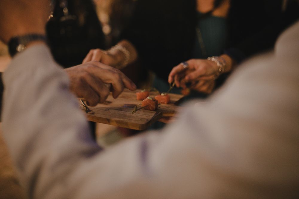 Hands serving food at a dining event with warm ambient lighting.