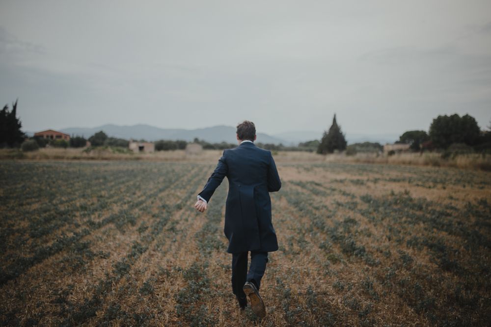 Figure walking away on dirt path through countryside field.