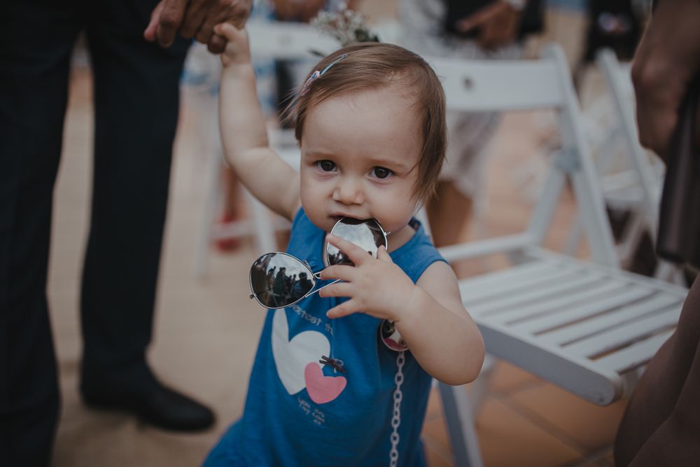 A small child in blue clothing holds a camera during a celebration.