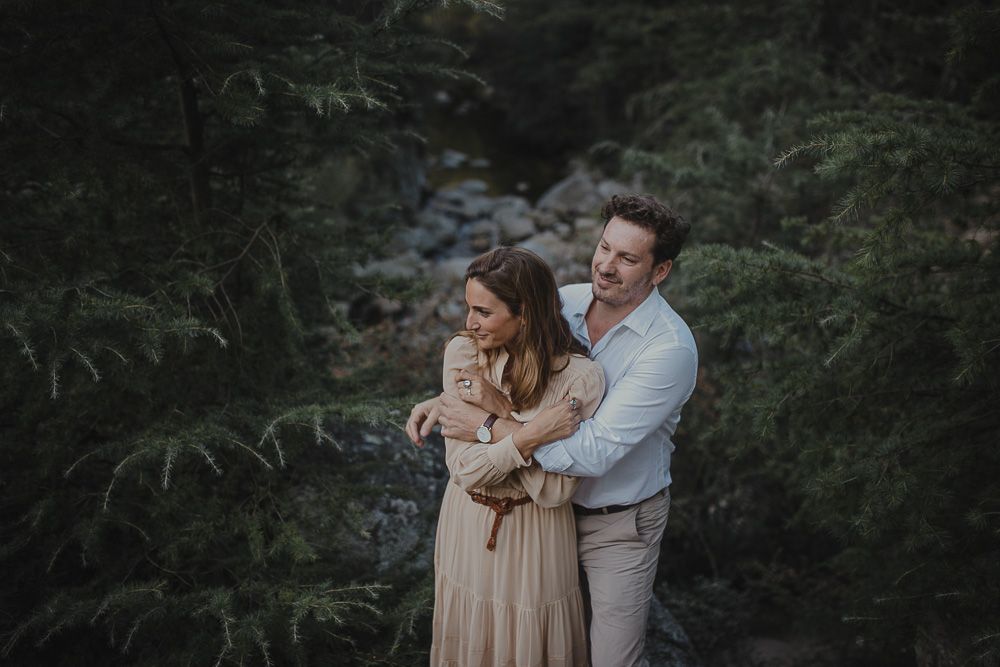 A tender moment captured between a couple by a forest stream.