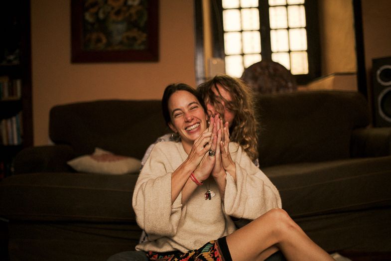 Candid laughter shared on a gray couch in a warmly lit living room.