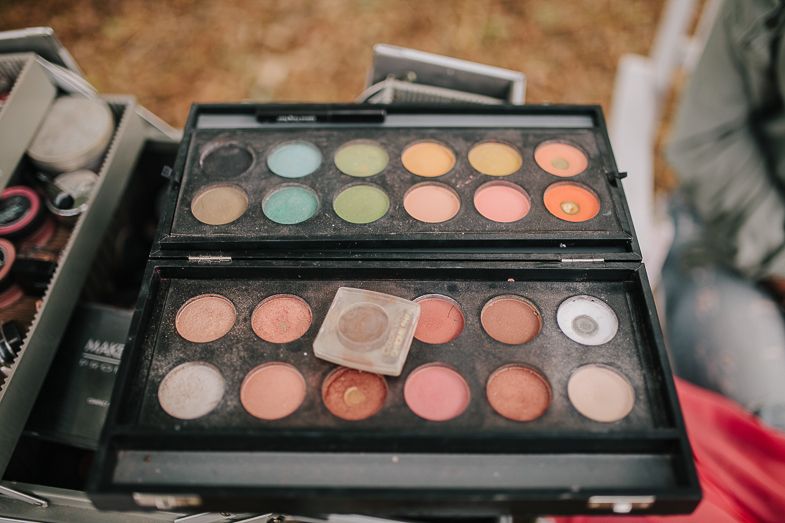 Palette of colorful eyeshadows and blushes displayed in a professional makeup case.
