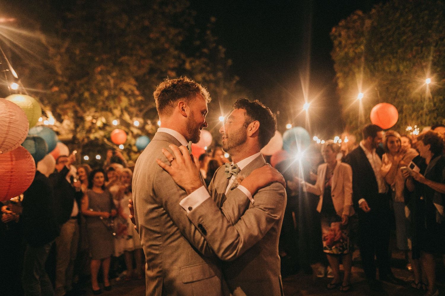 Couple sharing intimate dance moment under festive outdoor lighting with lanterns.