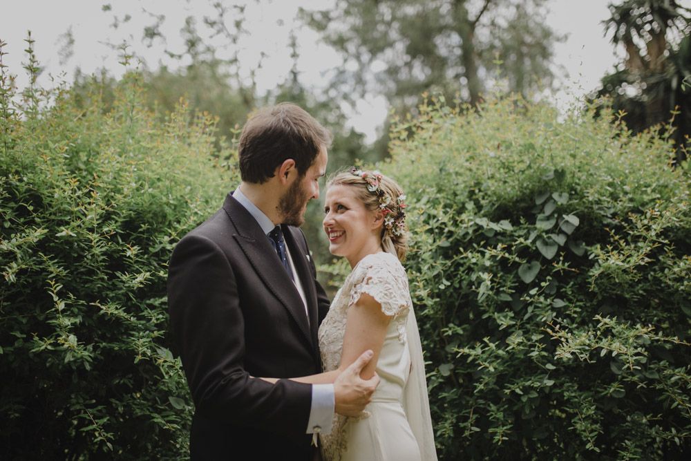 Joyful wedding portrait in a lush garden setting with natural lighting.