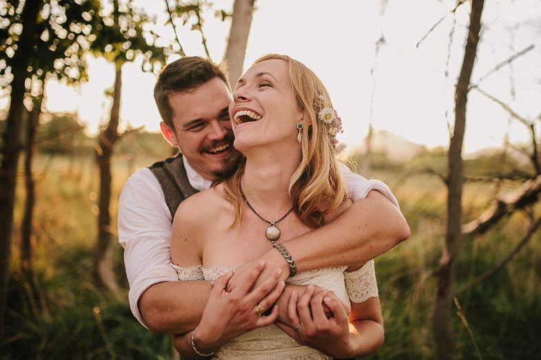 A joyful wedding moment captured in golden sunlight among autumn trees.