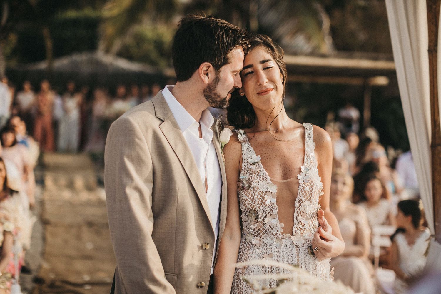 A romantic beach wedding moment with the couple in elegant attire against a sunset backdrop.