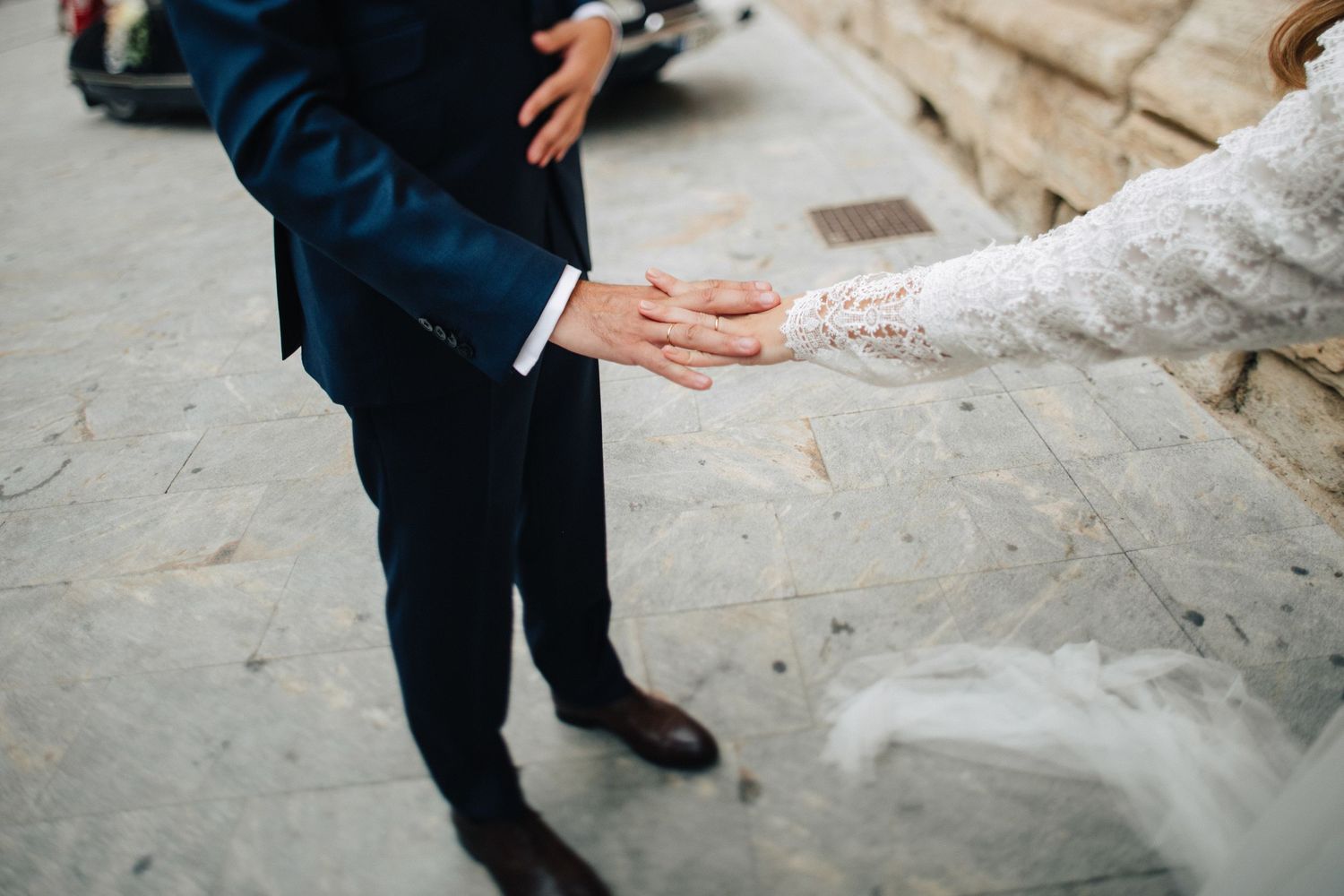 Close-up shot of hands reaching toward each other on stone steps.