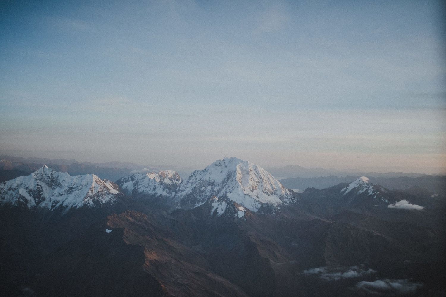 Snow-capped mountain peaks under a blue sky with dramatic ridgelines stretching into the distance.