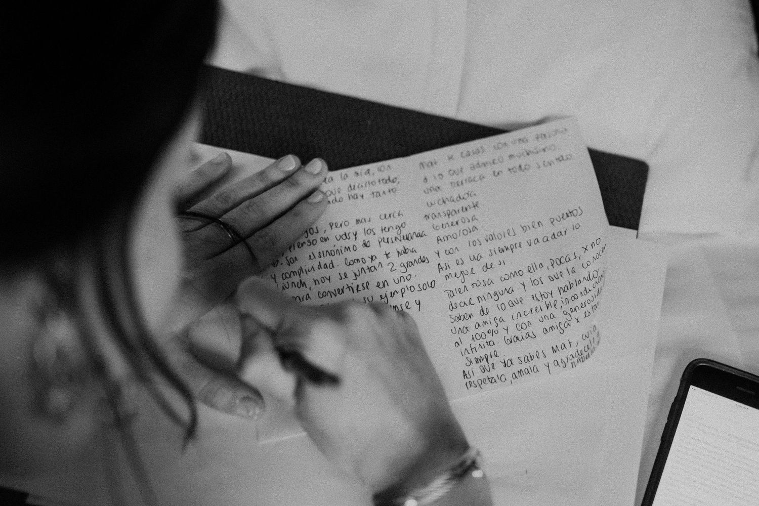 Handwritten note being held against white background in monochrome.
