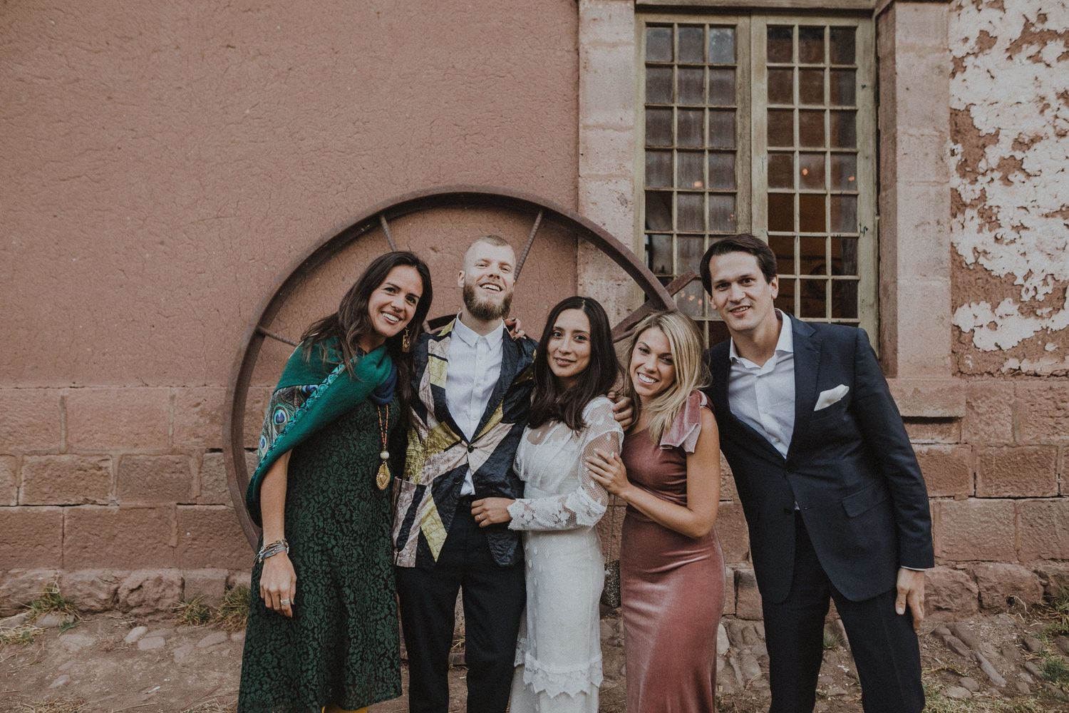A group poses together under a stone archway during a formal celebration event.