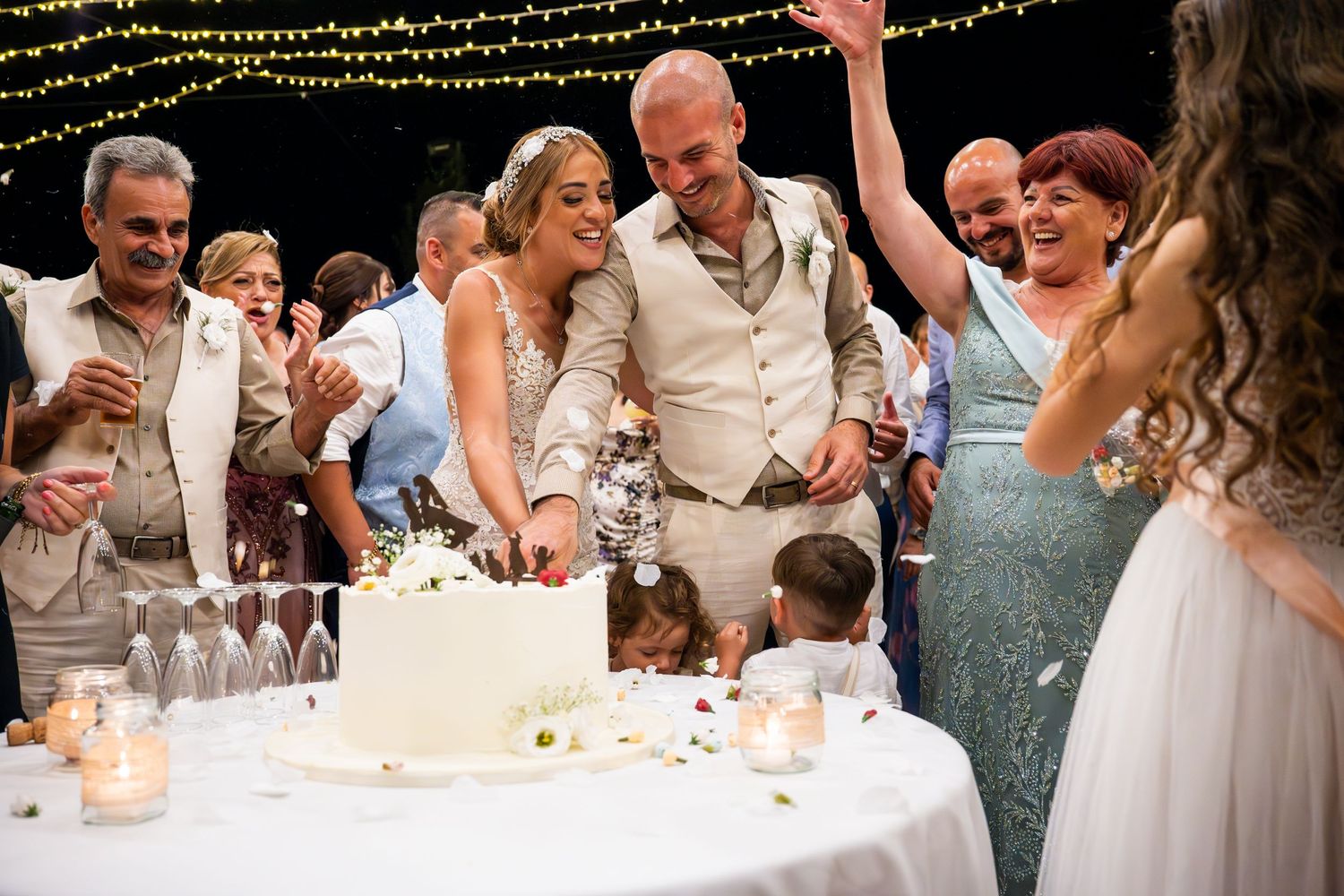 Wedding reception party with string lights overhead as guests celebrate at decorated tables.