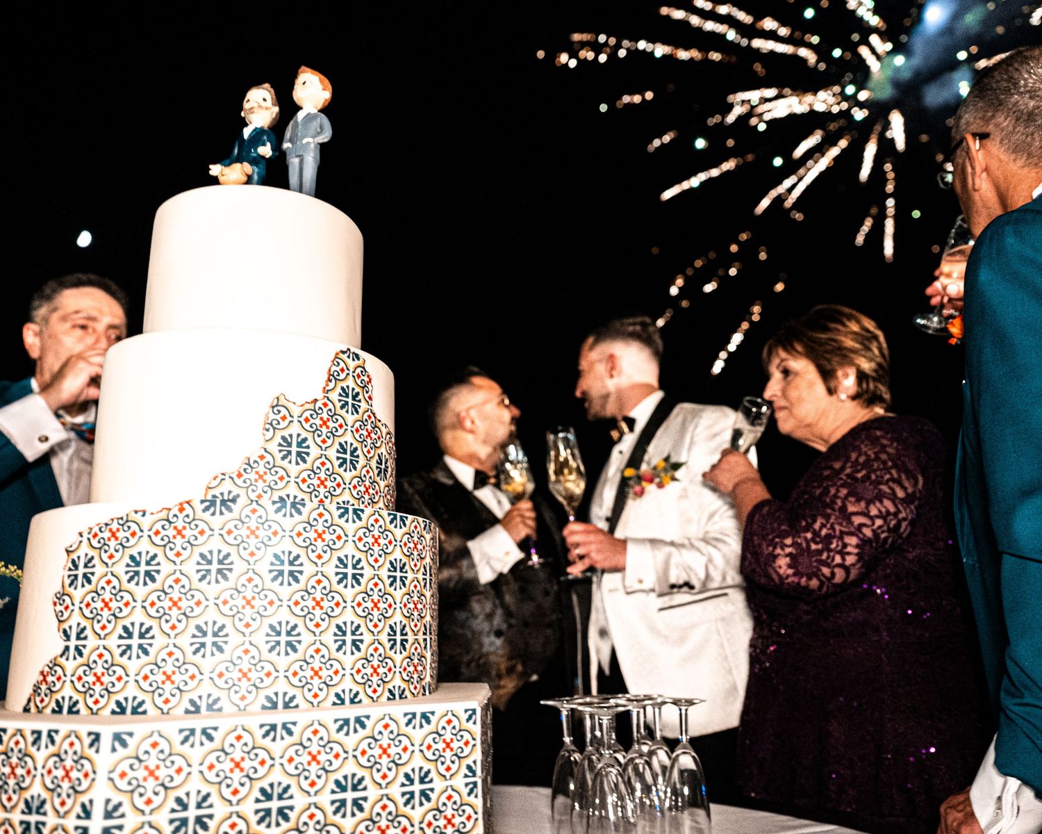 Wedding reception guests toasting with champagne glasses near an ornate white column.