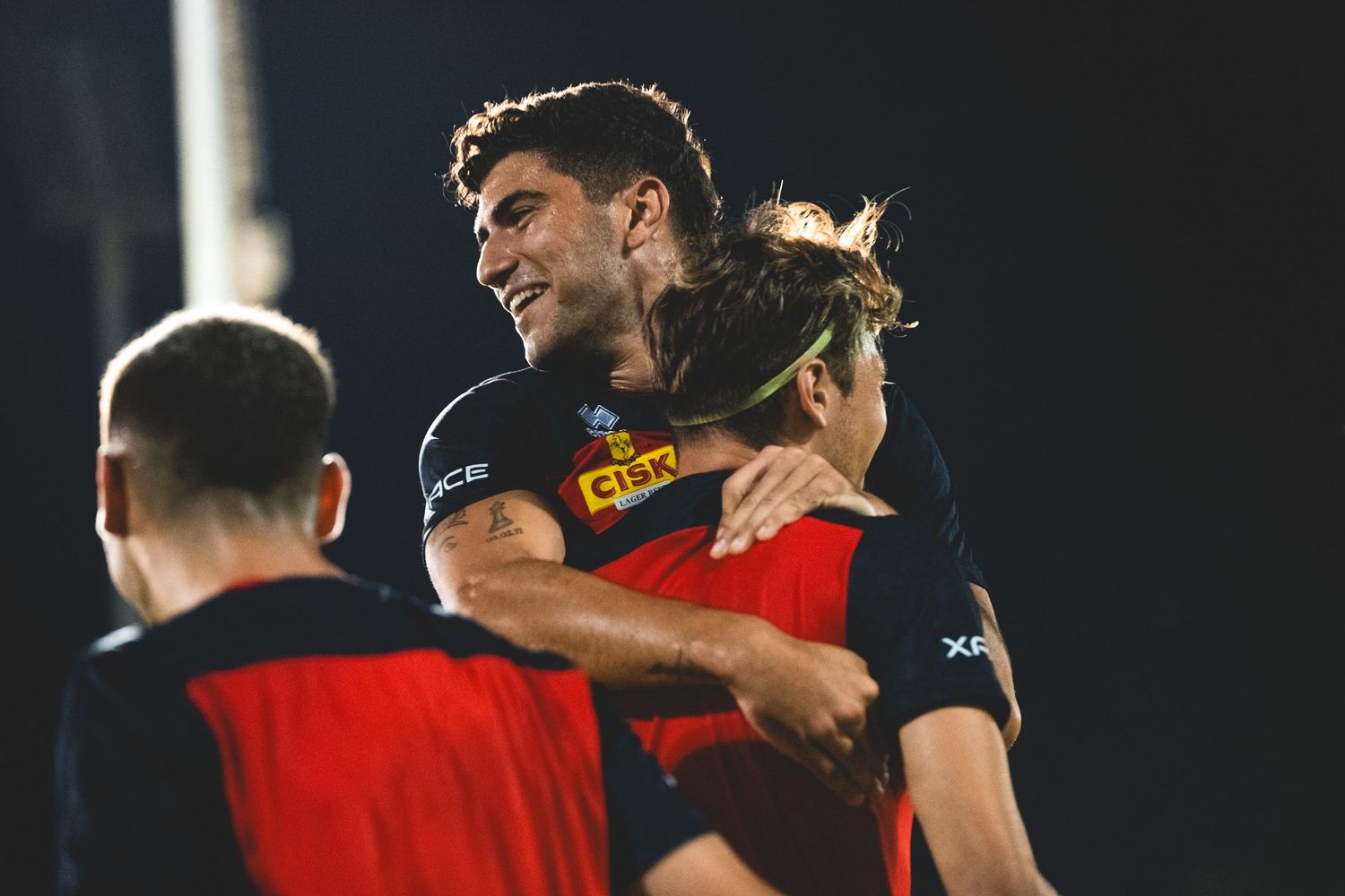 Soccer players in red uniforms training during a nighttime practice session.