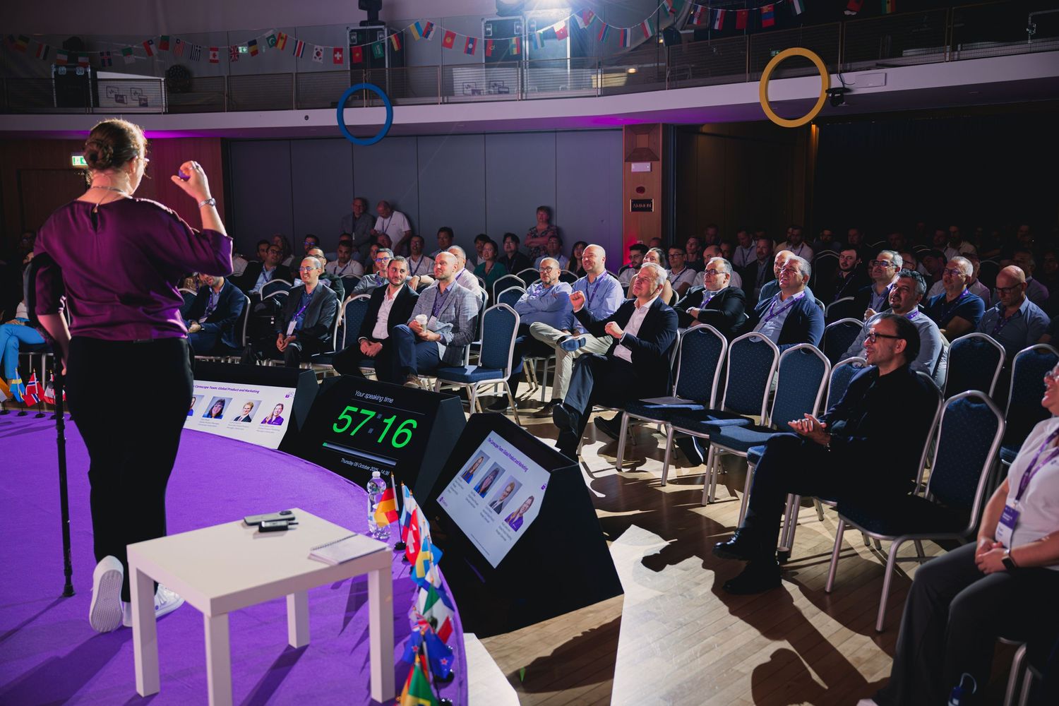 Corporate event space with theater-style seating and purple stage lighting.