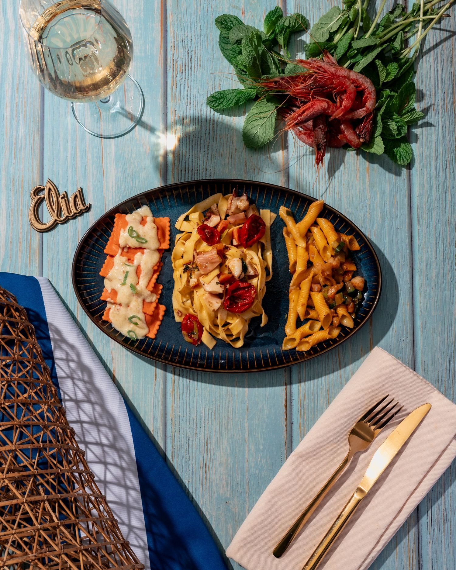 Elegant table setting with plates of food and wine glasses on a rustic blue wooden surface.