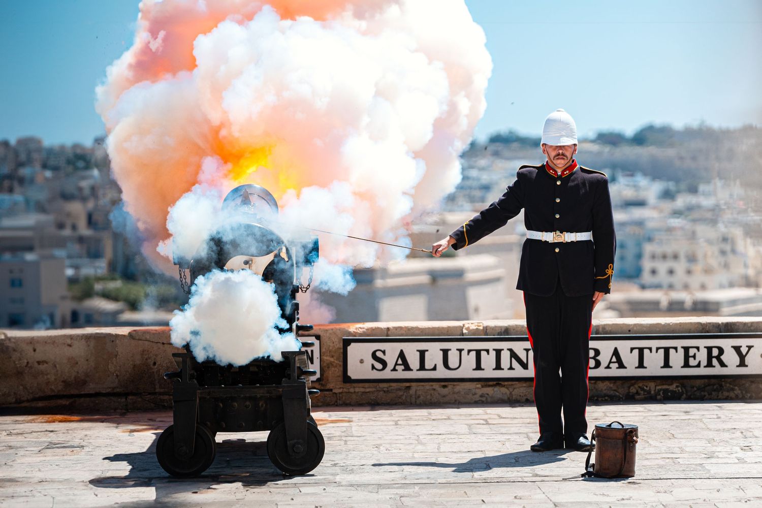 Colorful smoke display at Saluting Battery with pink and orange clouds against city backdrop.
