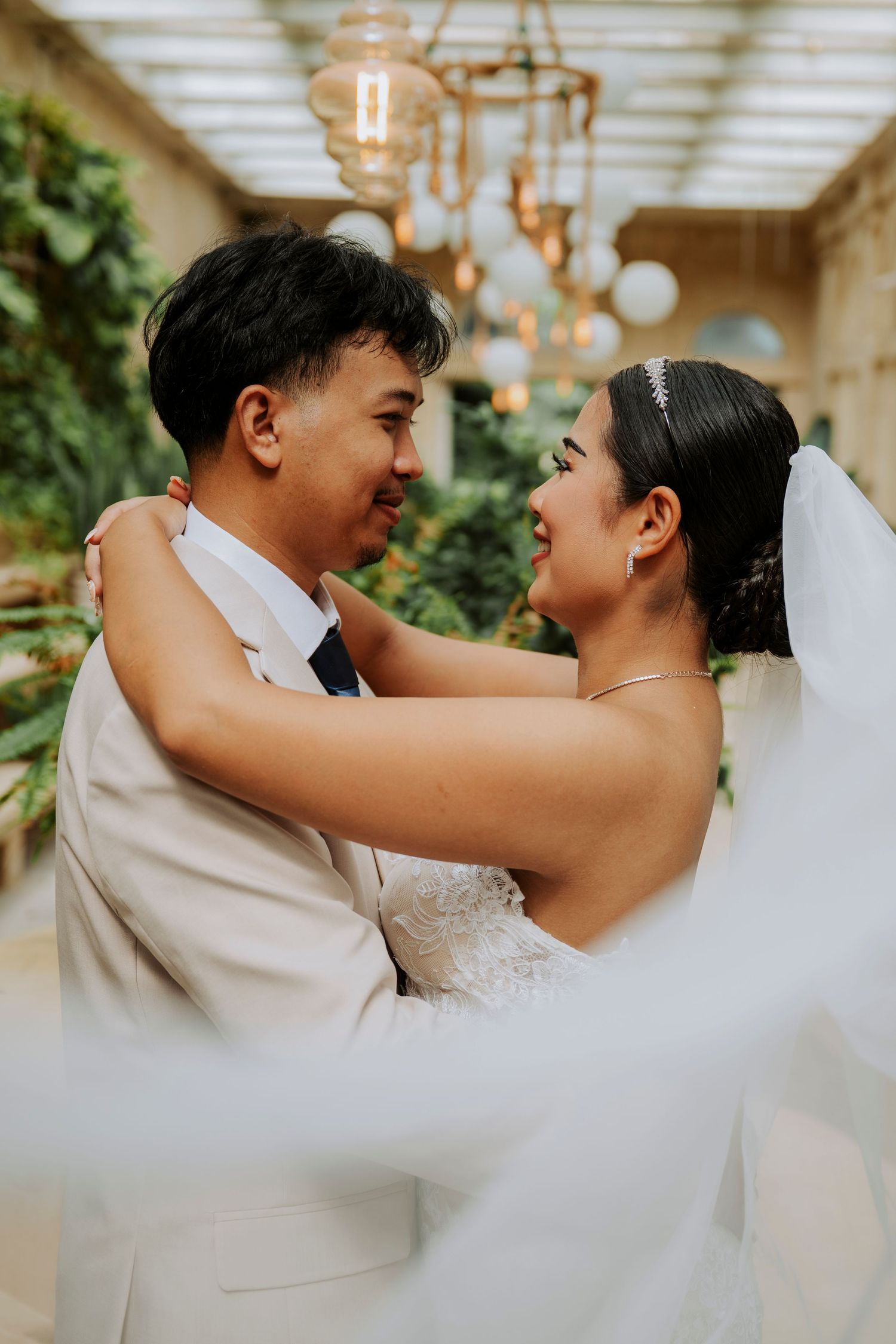A joyful bride and groom share an intimate embrace, gazing lovingly at each other in an elegant garden venue.