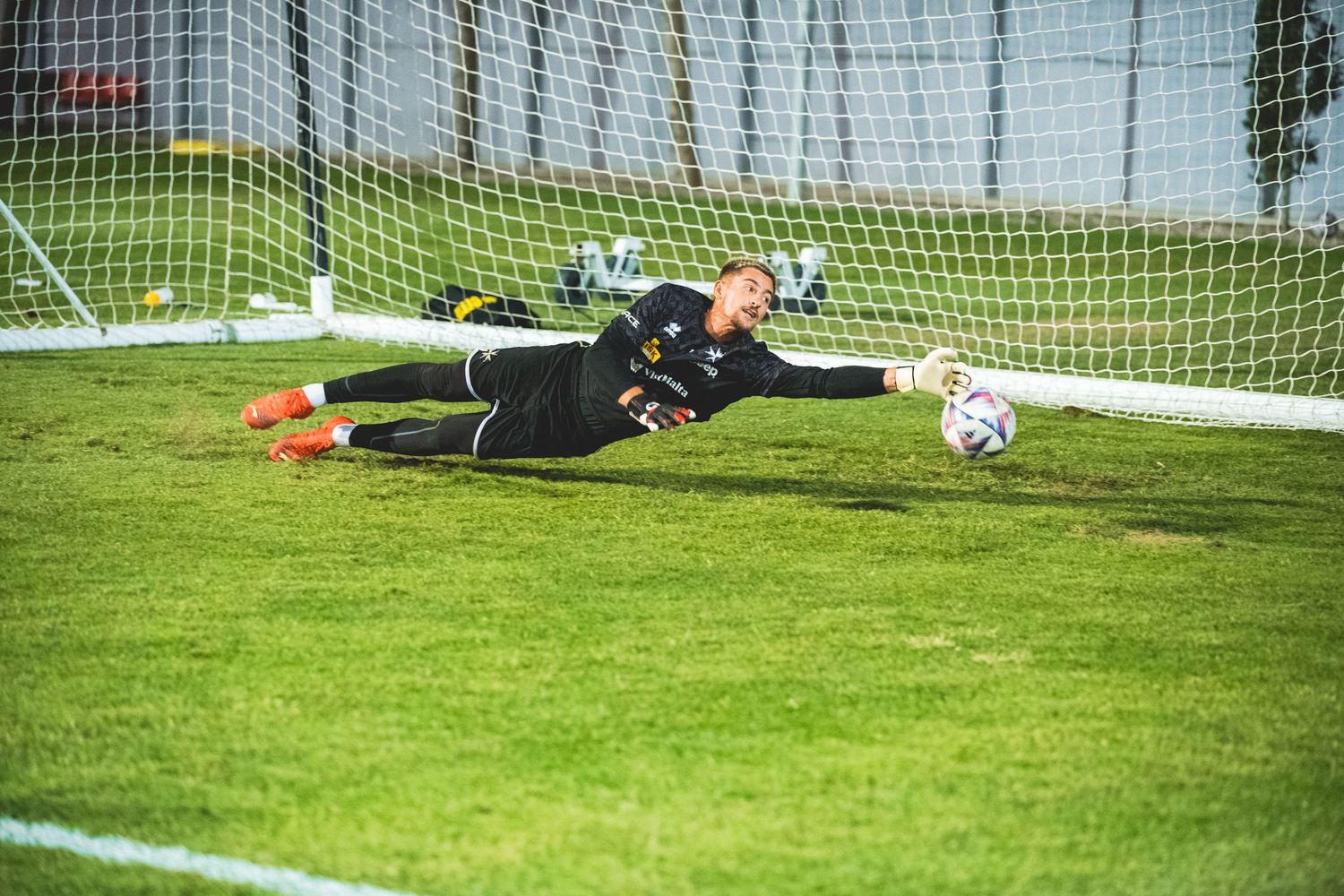 Soccer goal net with players practicing shots during a training session.