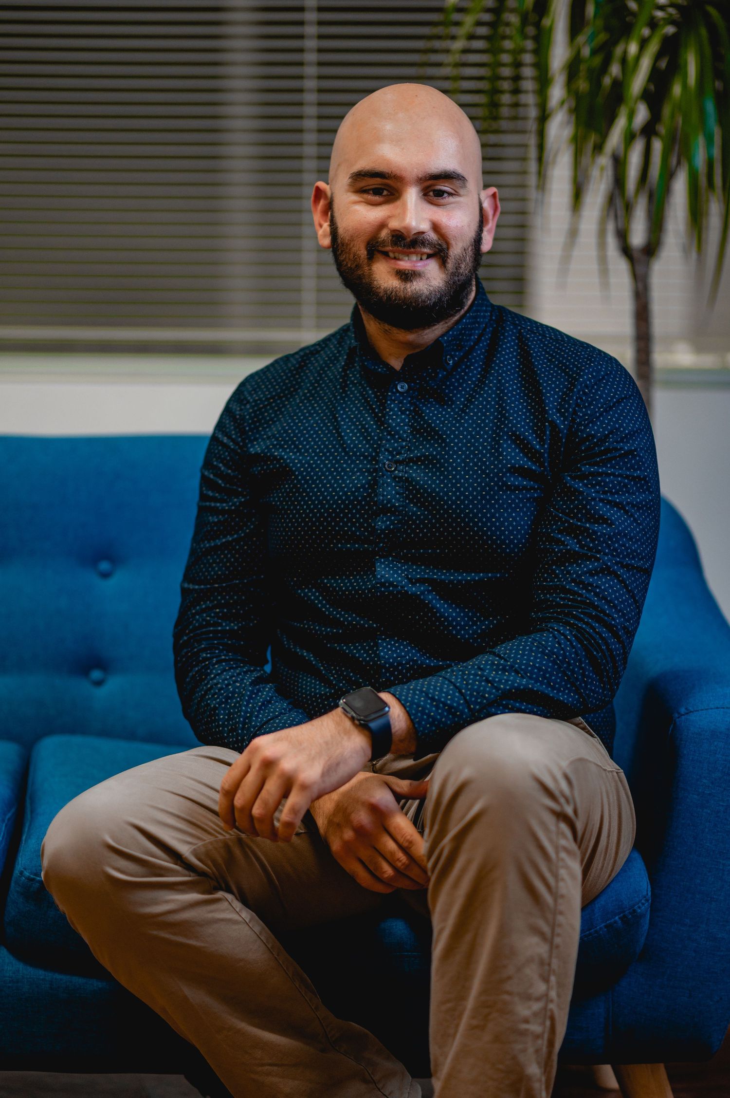 Person wearing a navy polka dot shirt sitting comfortably on a bright blue couch.