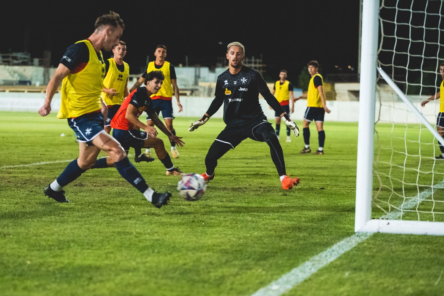 Soccer action shot showing players scrambling near the goal during a match.