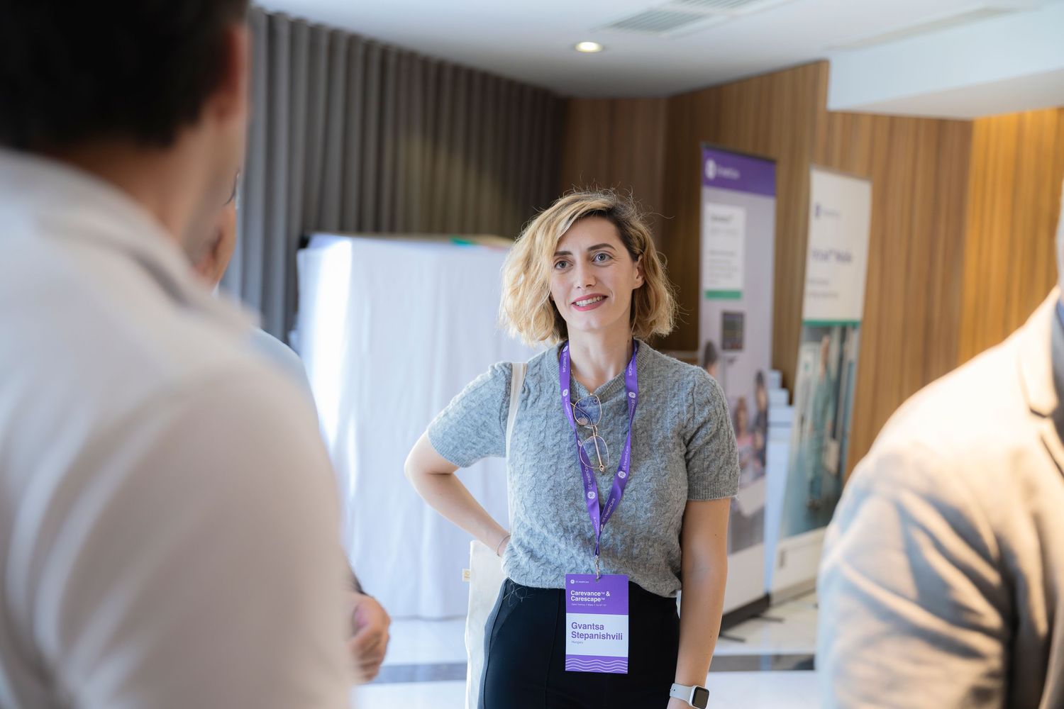 Conference attendees networking in brightly lit modern office hallway.
