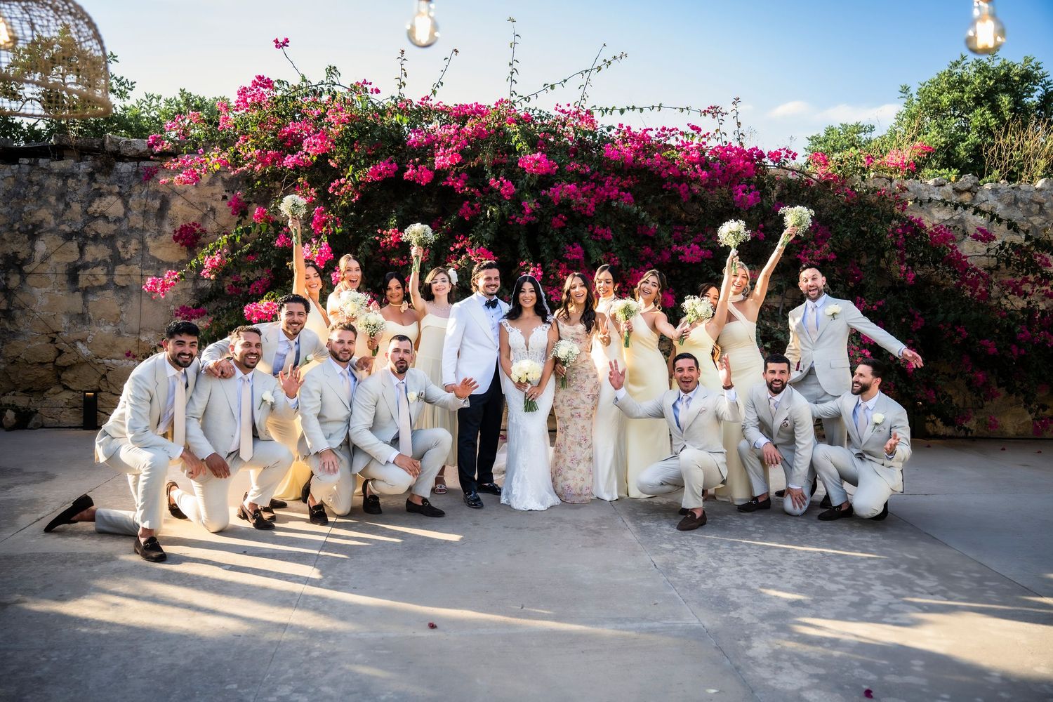 Wedding party in light colored attire posing together outdoors.