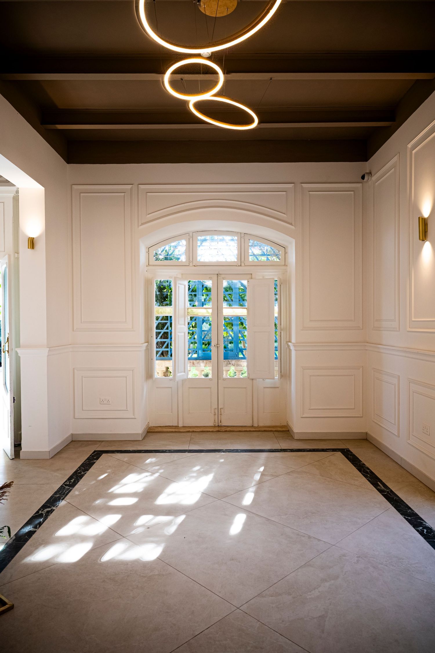 Modern white room interior with circular lighting fixtures and large windows casting natural light.