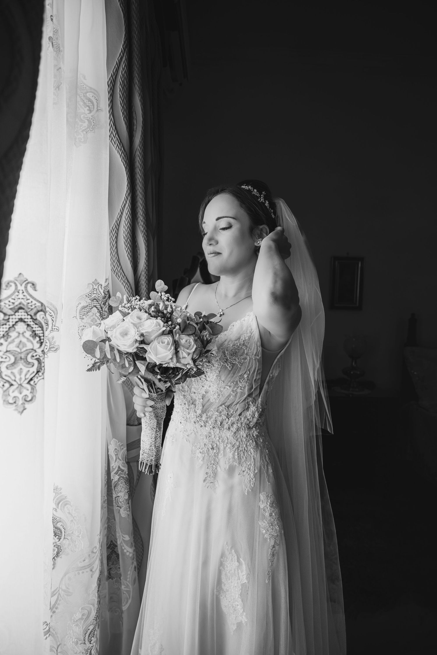 Black and white bridal portraits showing an elegant lace wedding dress and veil against a window.