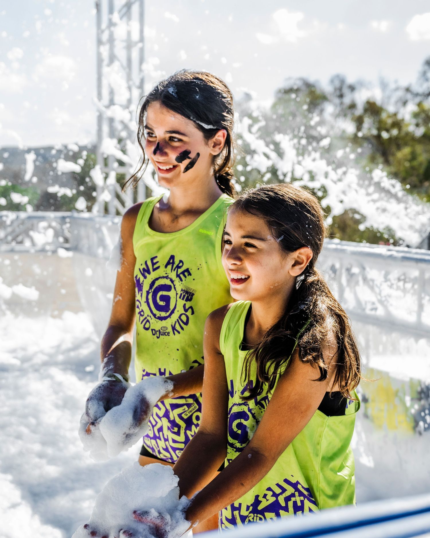 Participants enjoying water features at outdoor summer event wearing neon athletic gear.