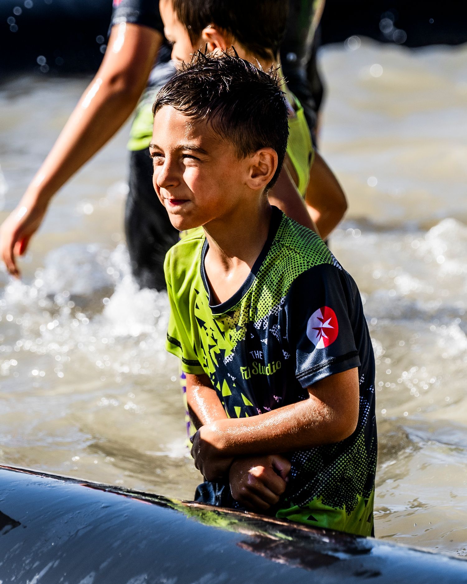 Young participant navigating water obstacle during outdoor adventure race.