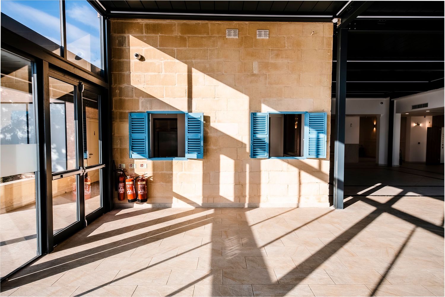 Contemporary interior space with large windows casting dramatic shadows on the floor.