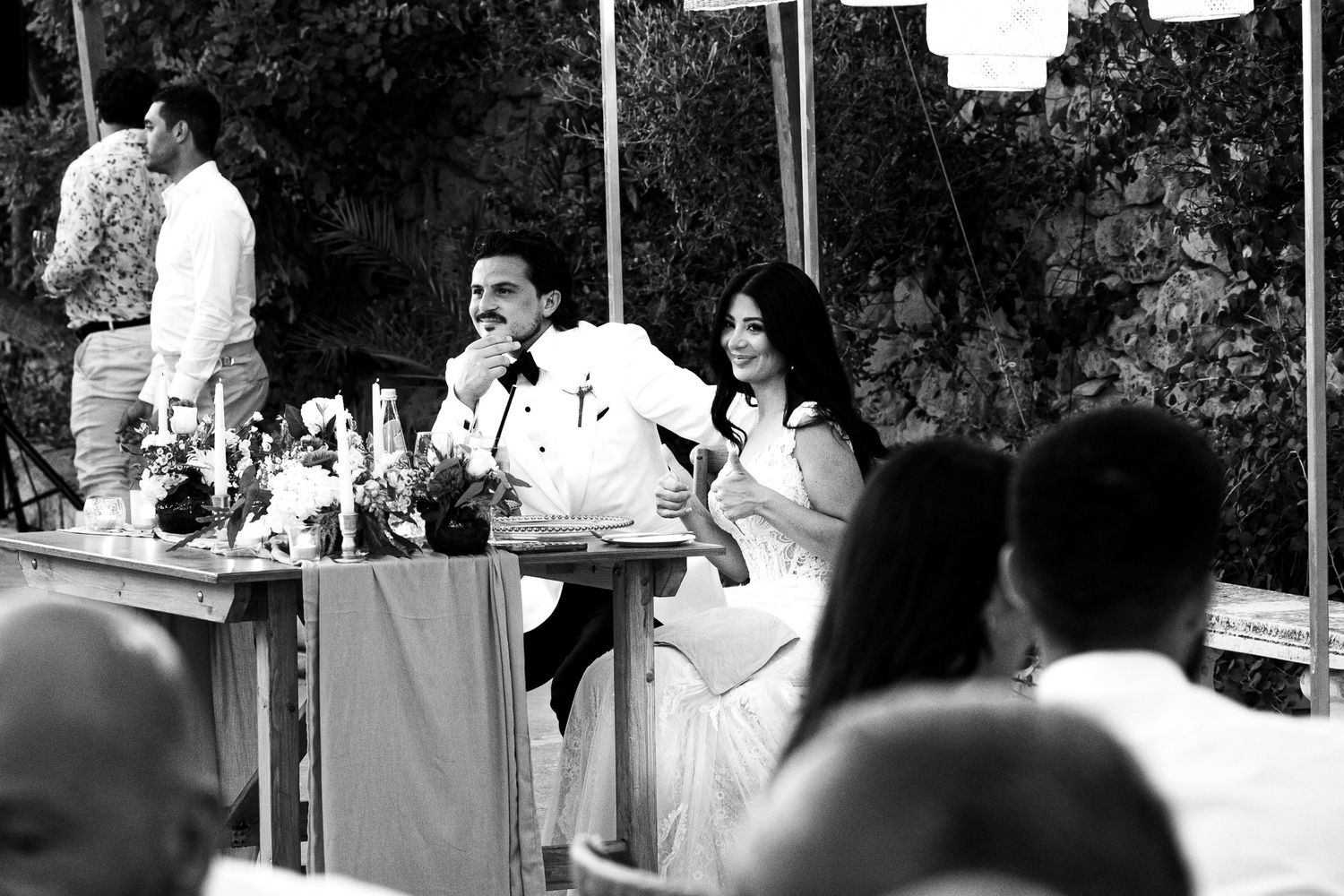 Black and white photo of wedding guests seated at outdoor reception.