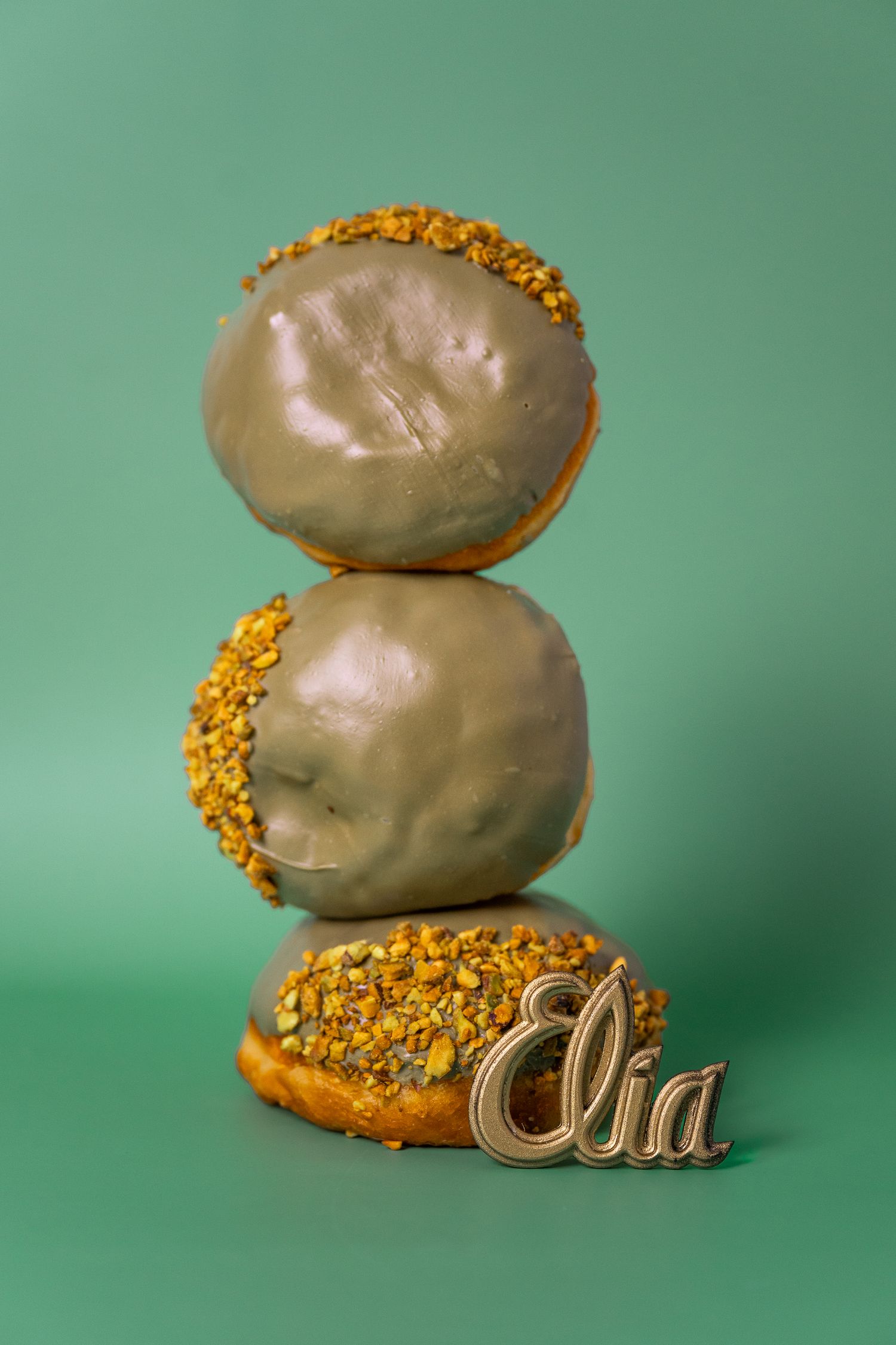 Glazed pastries topped with gold sprinkles arranged artistically on a mint green background.