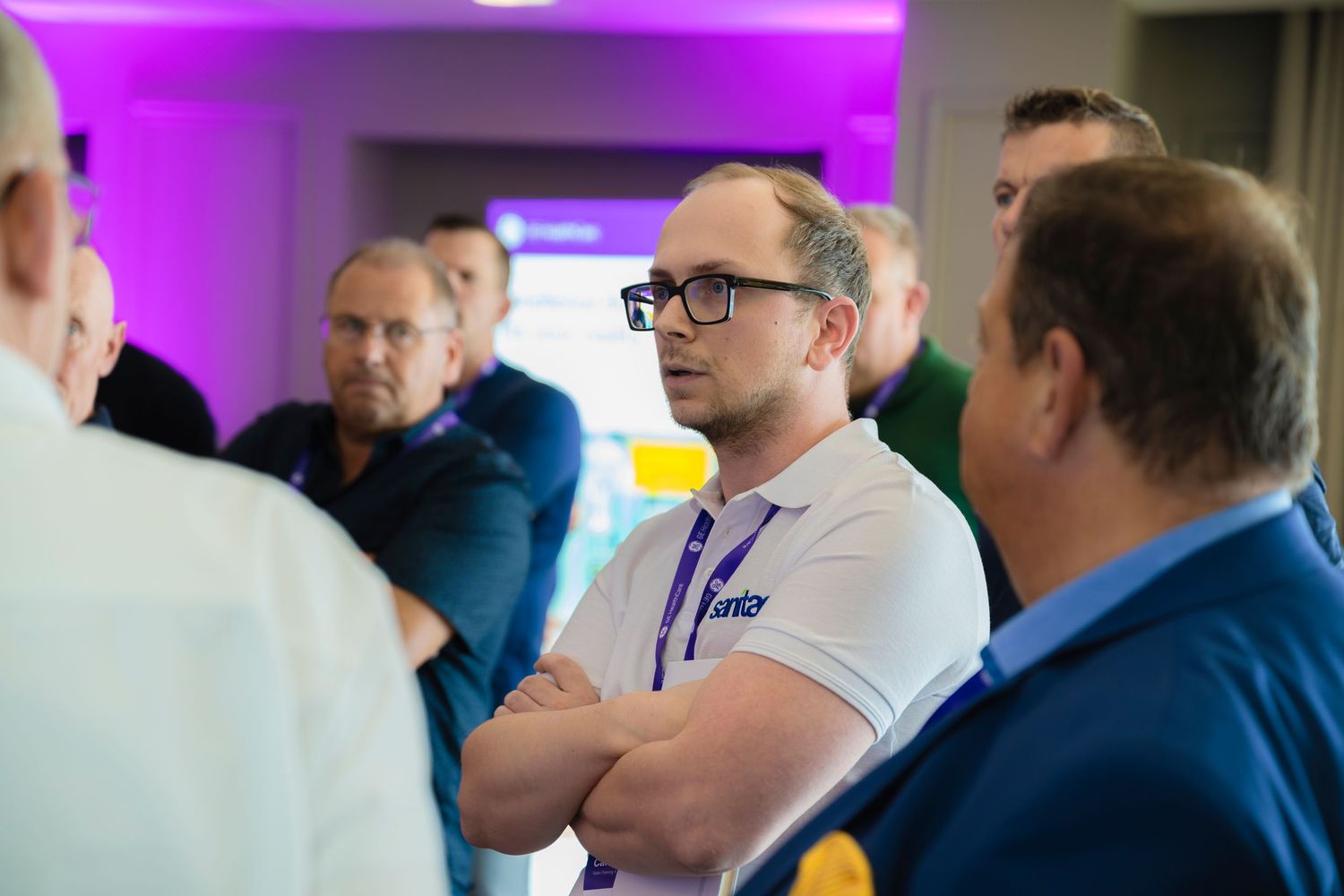 Business professionals networking at conference with purple-lit backdrop.