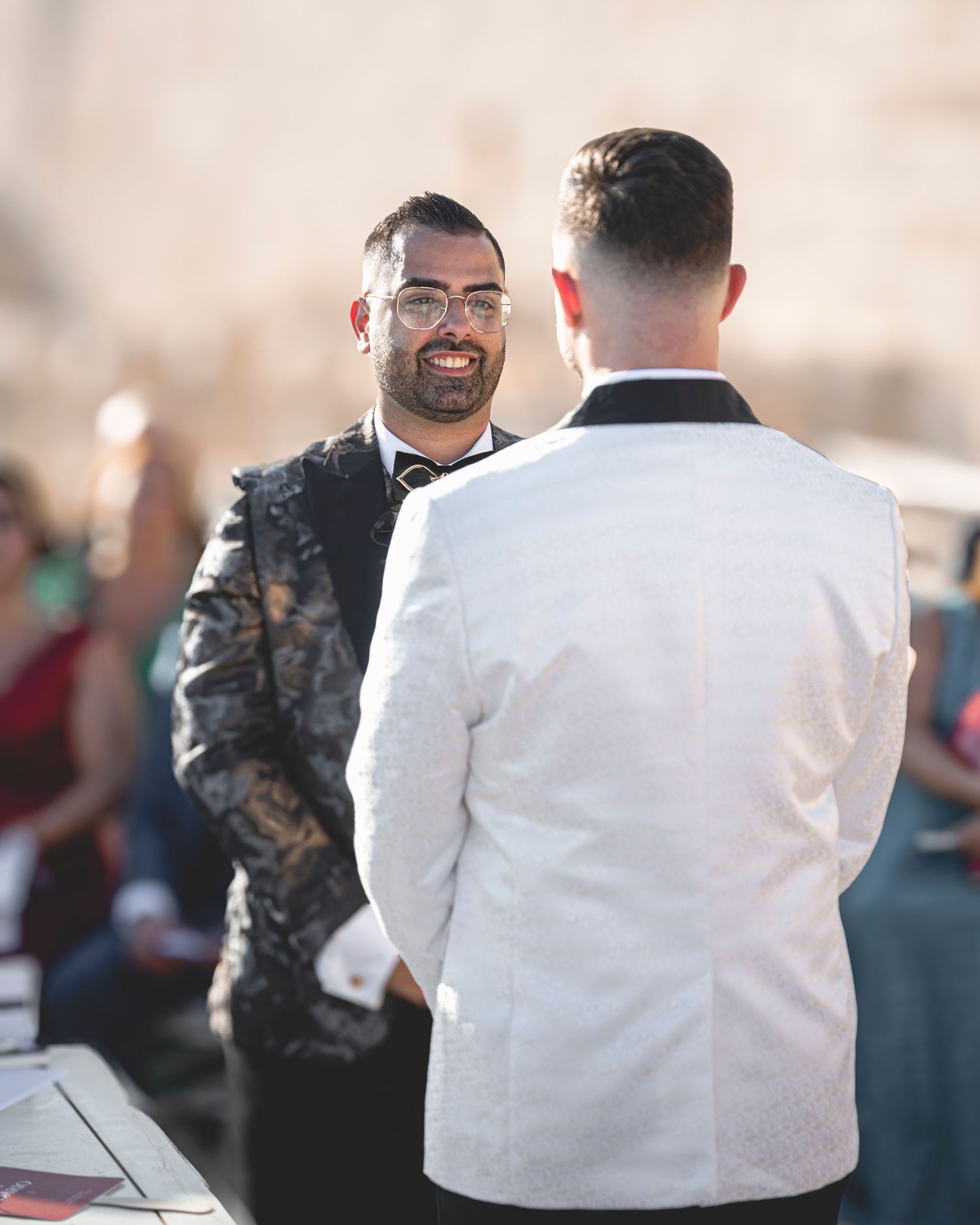 Formal event with guests in white and patterned attire mingling at tables.