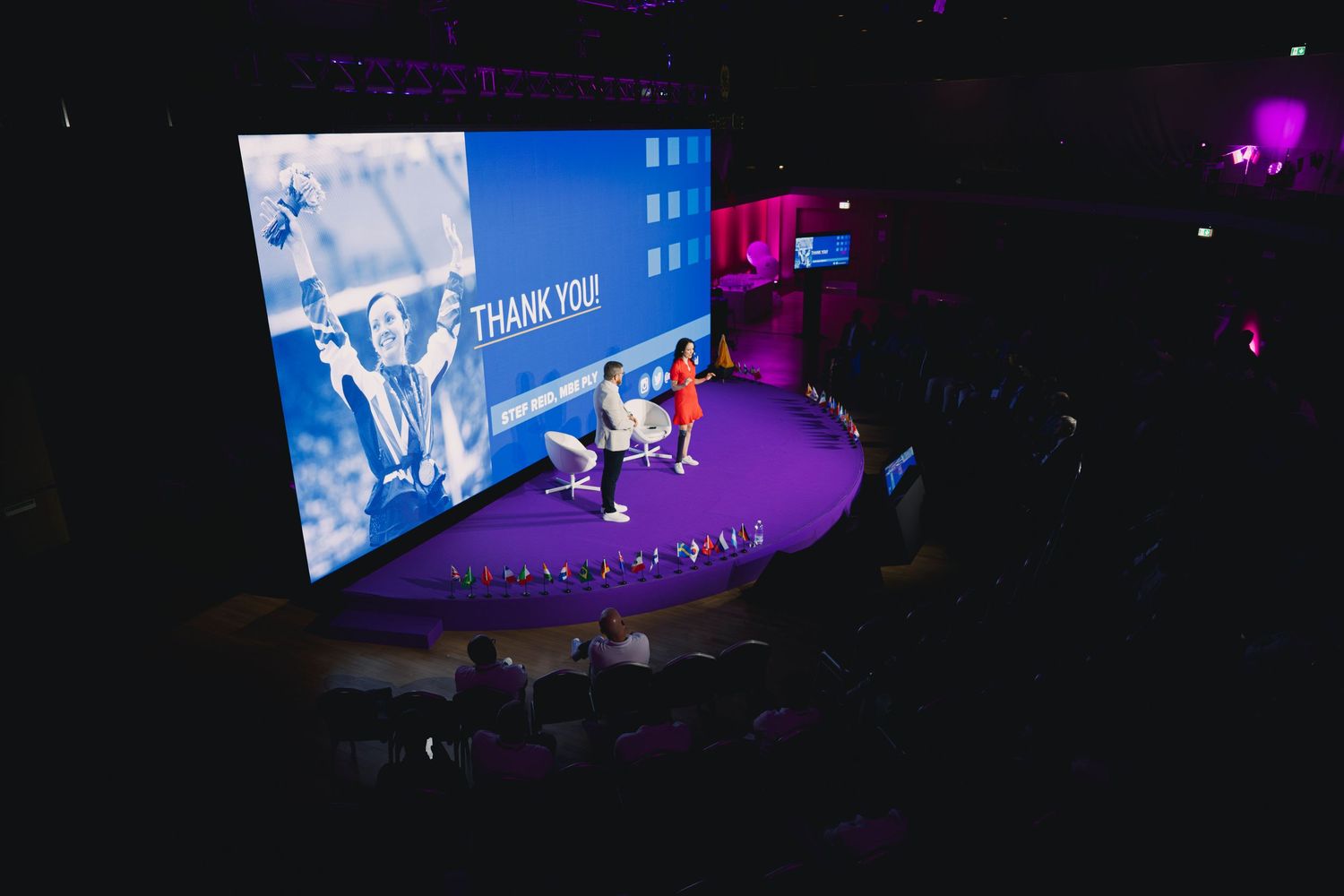 Wide view of conference hall with presentation screen and dramatic lighting effects.