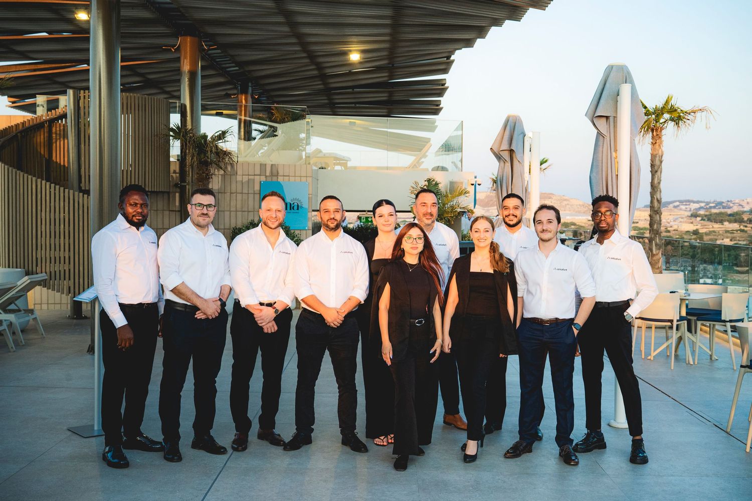 Professional service staff in formal attire pose together on an outdoor terrace venue.