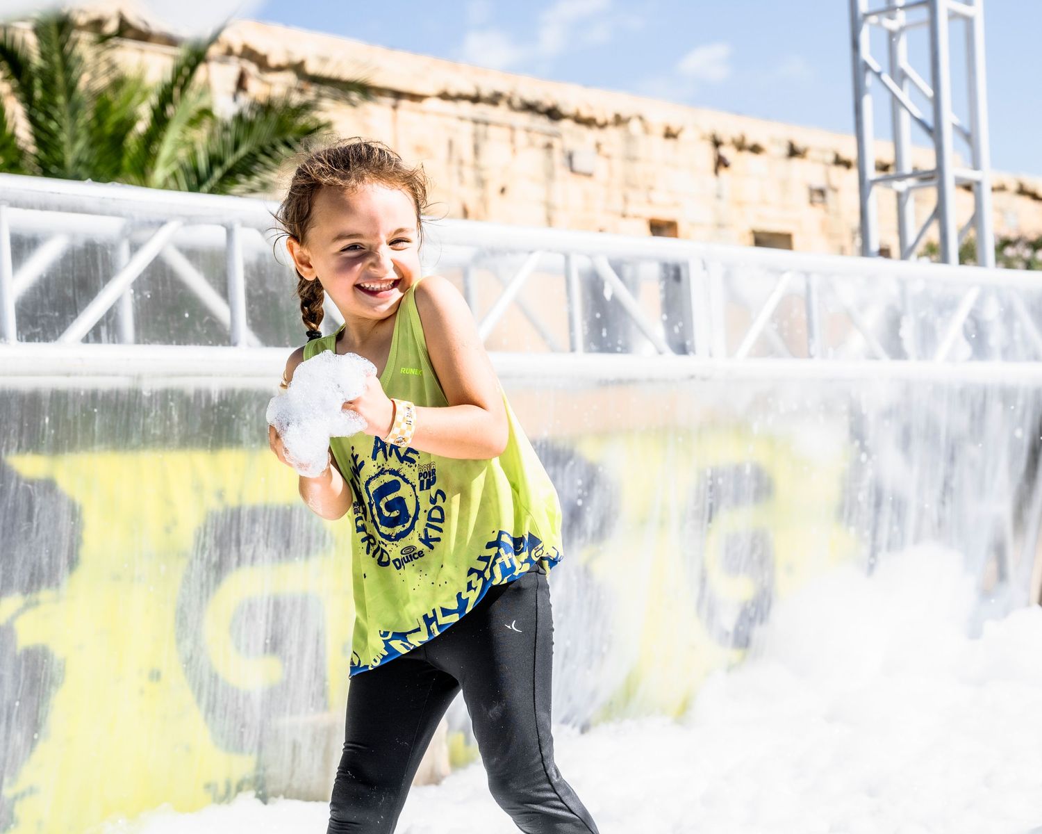 Young participant in neon yellow shirt enjoying an obstacle course race.