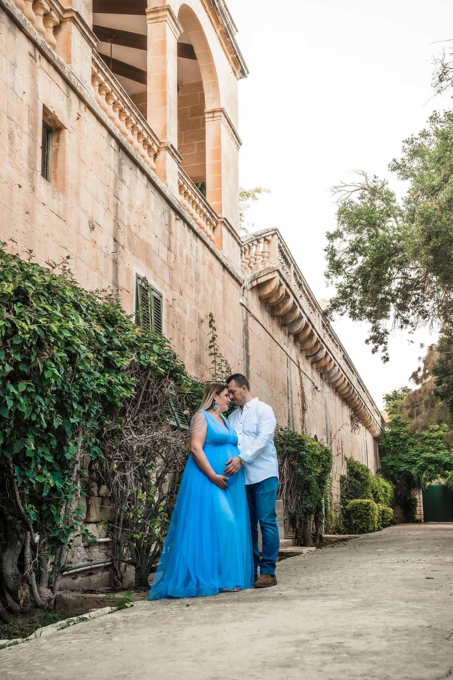 Romantic couple photoshoot against historic stone building with ivy covered walls.