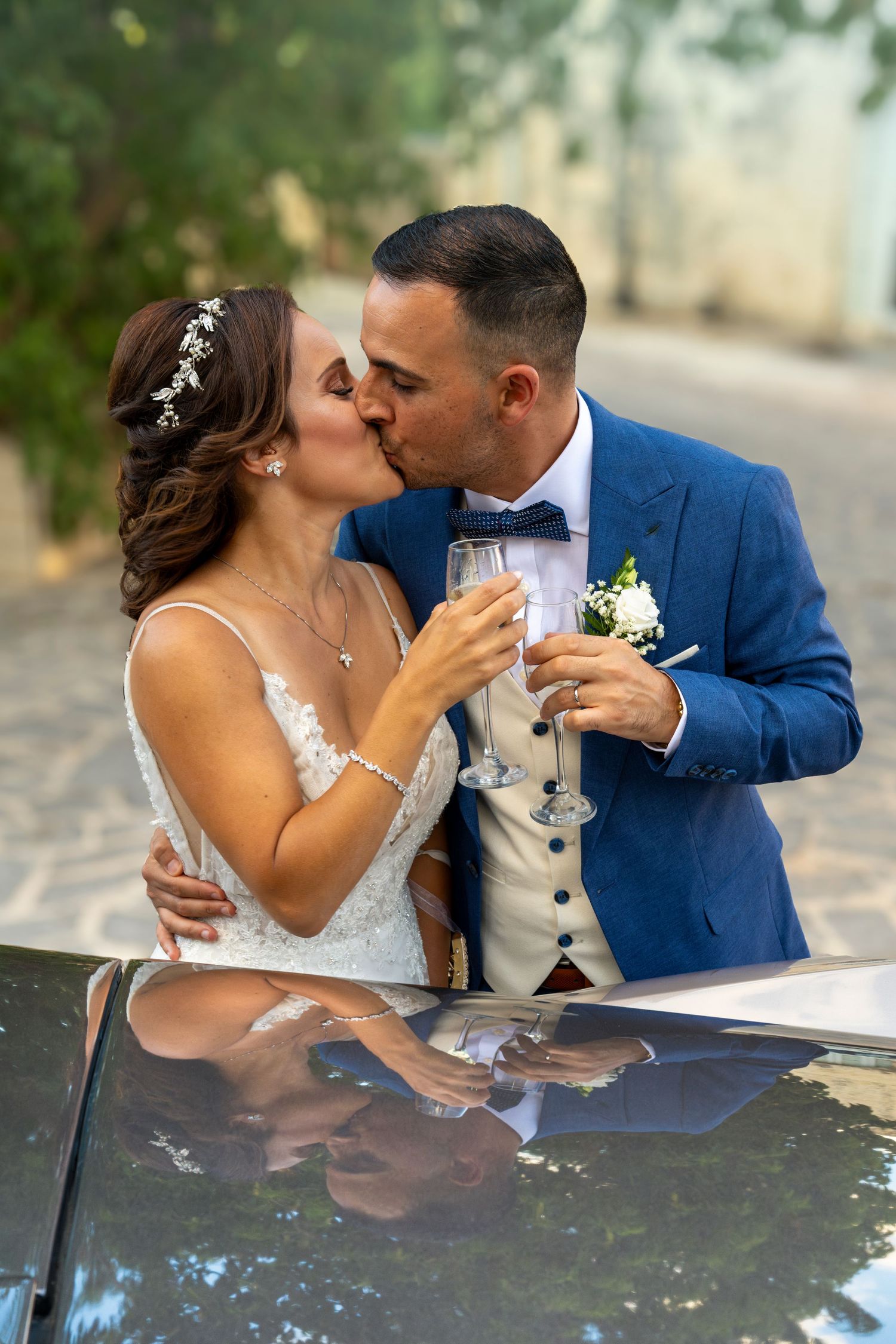 Romantic wedding portraits taken against a car outdoors.