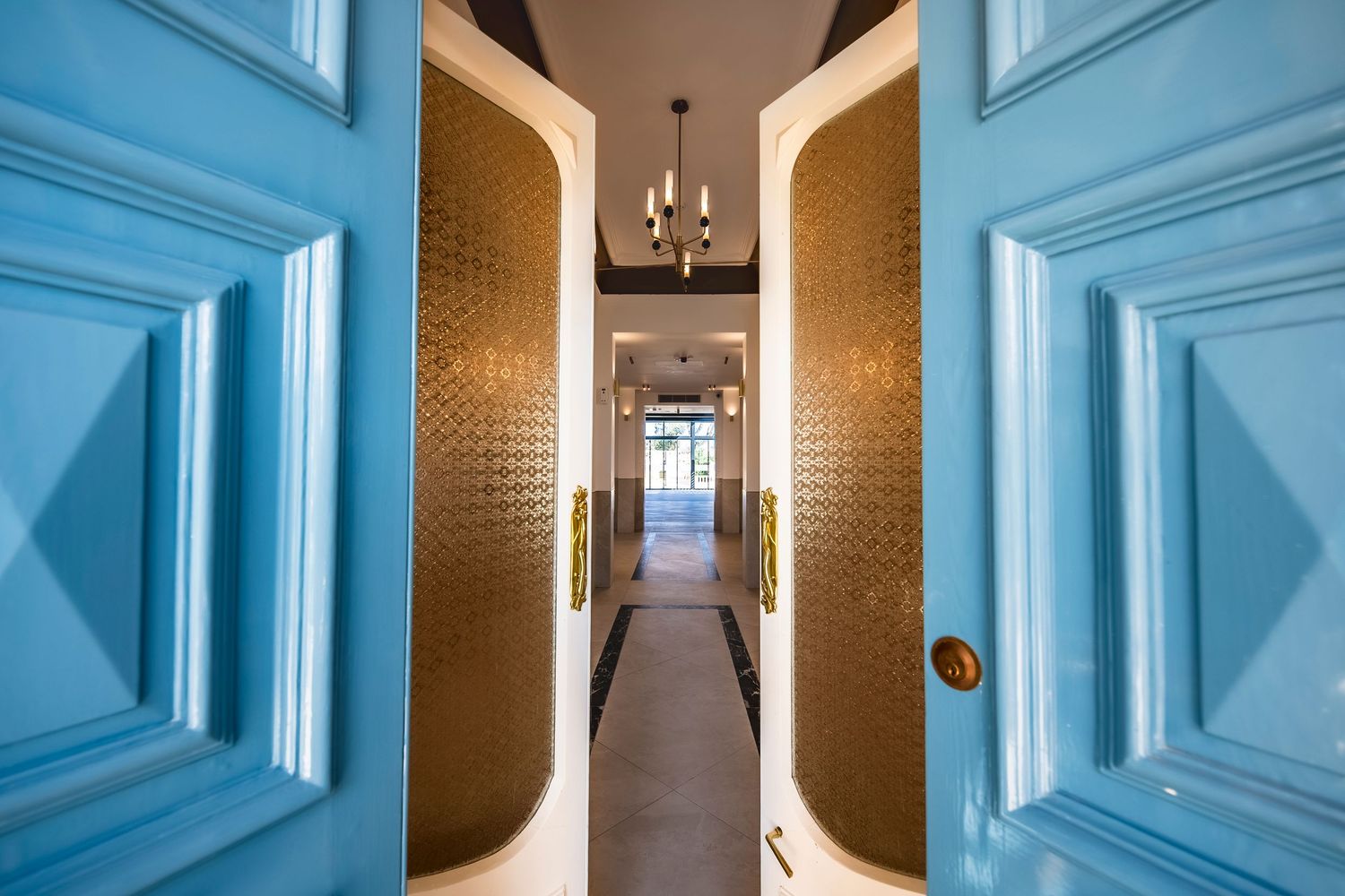 Hallway with bright blue doors and golden textured walls creating an elegant contrast.