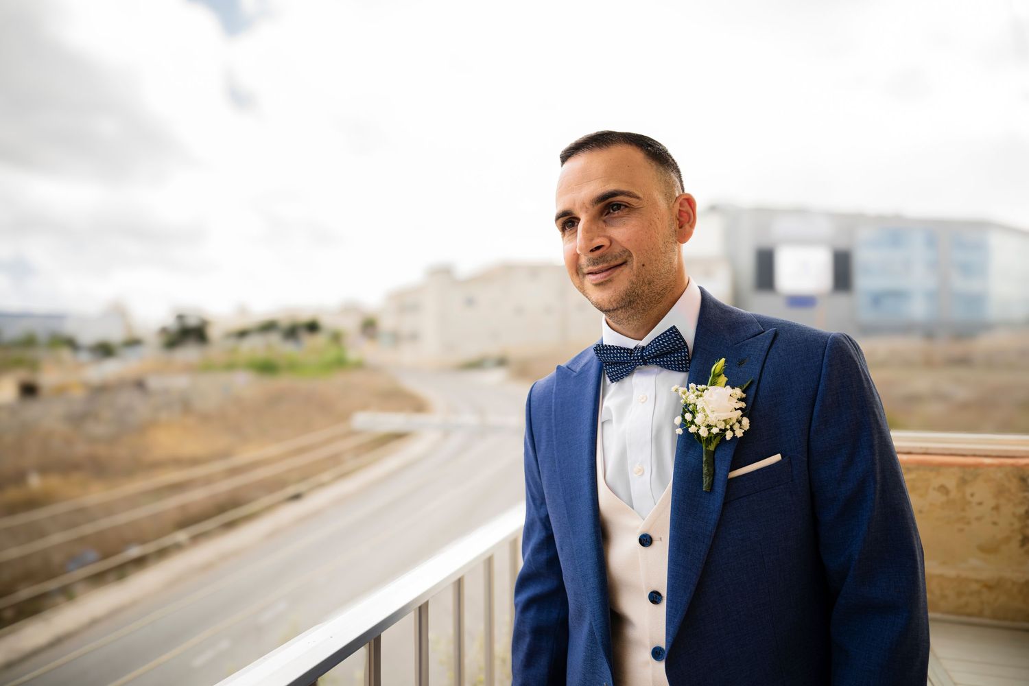 Groom portraits in navy blue suit outdoors on a cloudy day.