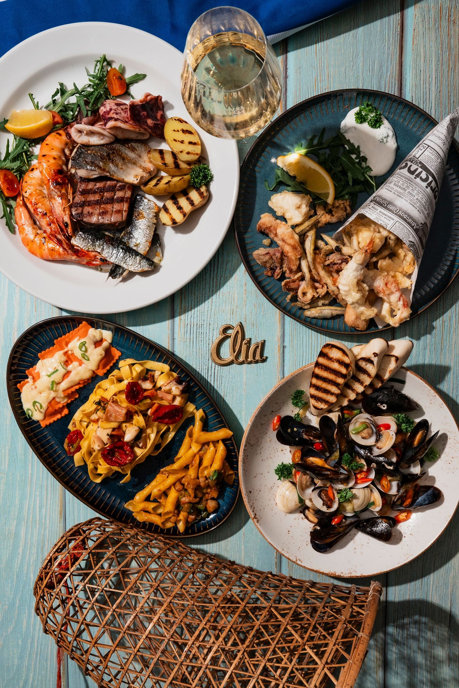 Seafood feast with grilled fish, shrimp, and vegetables served on blue plates.