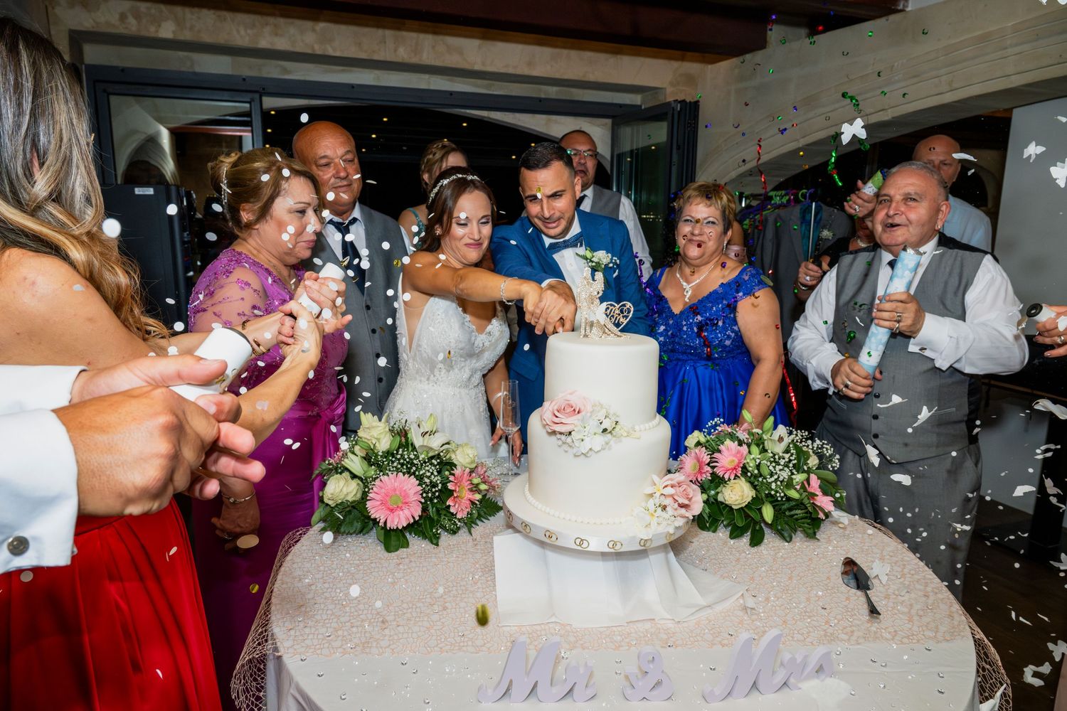 Wedding reception guests celebrating around the cake cutting.