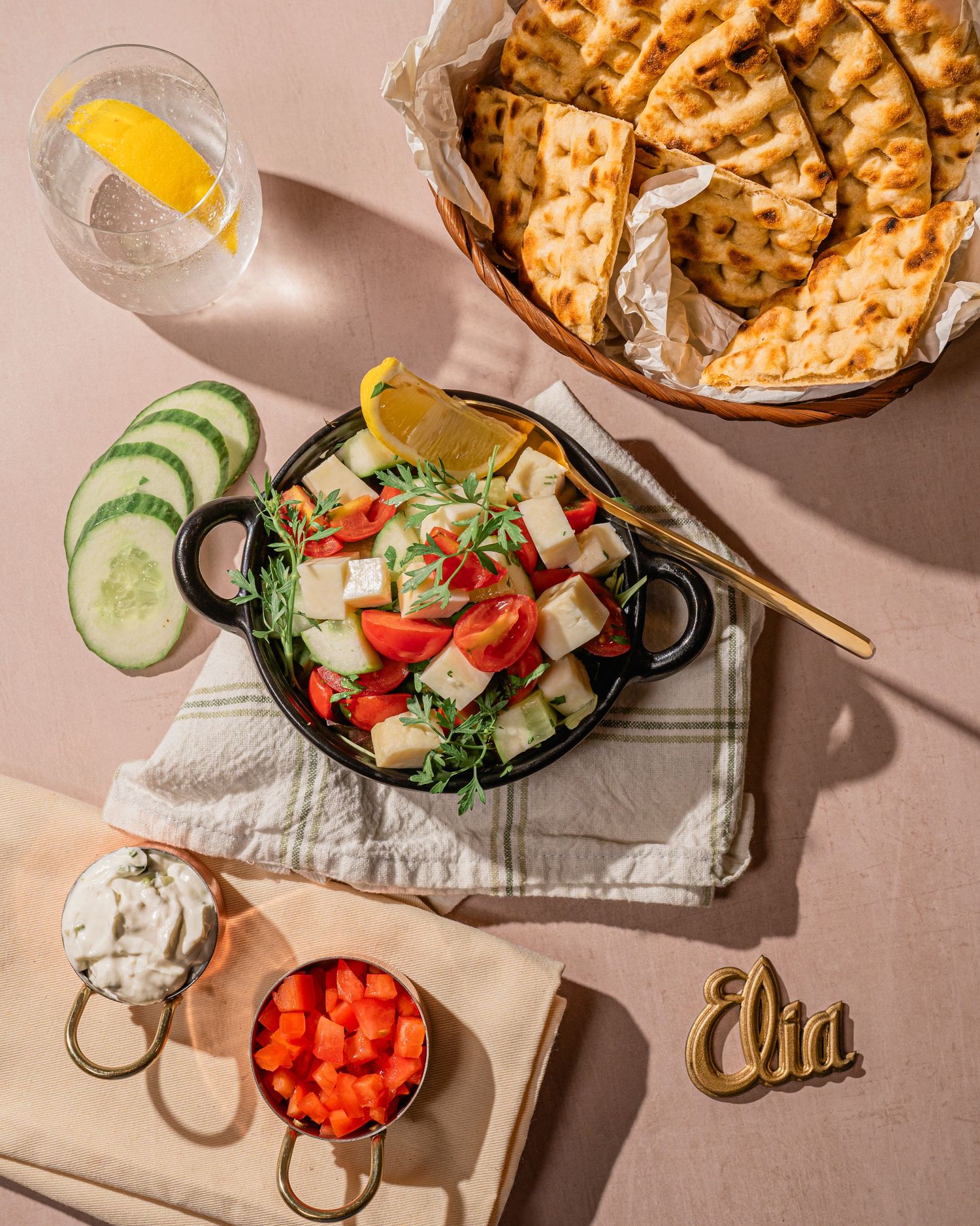Elegant table setting with fresh salad, bread, and appetizers arranged on plates with gold utensils.