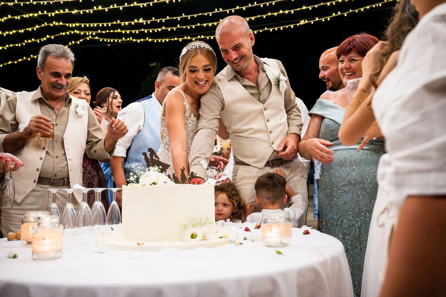 Wedding reception guests seated at tables with string lights overhead.