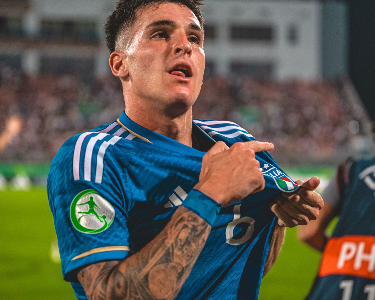 Close-up of soccer players celebrating in blue jerseys with stadium lights in background.