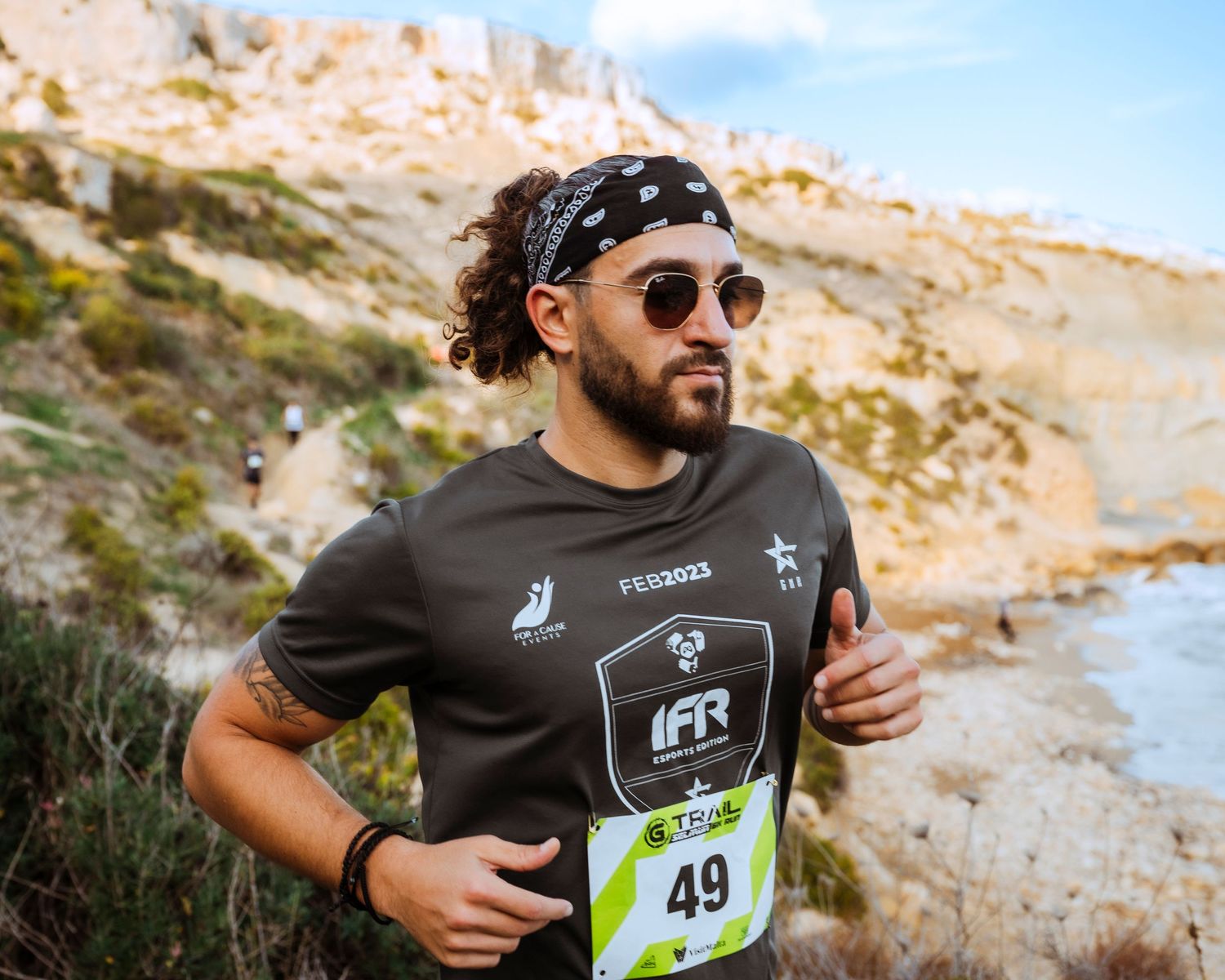 Runner wearing race bib navigates rocky desert terrain during an outdoor competition.