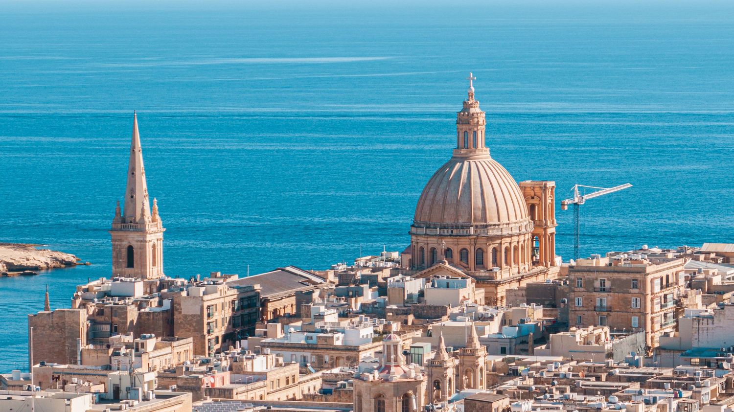 Panoramic view of Malta's coastal skyline with historic domed churches and Mediterranean architecture.