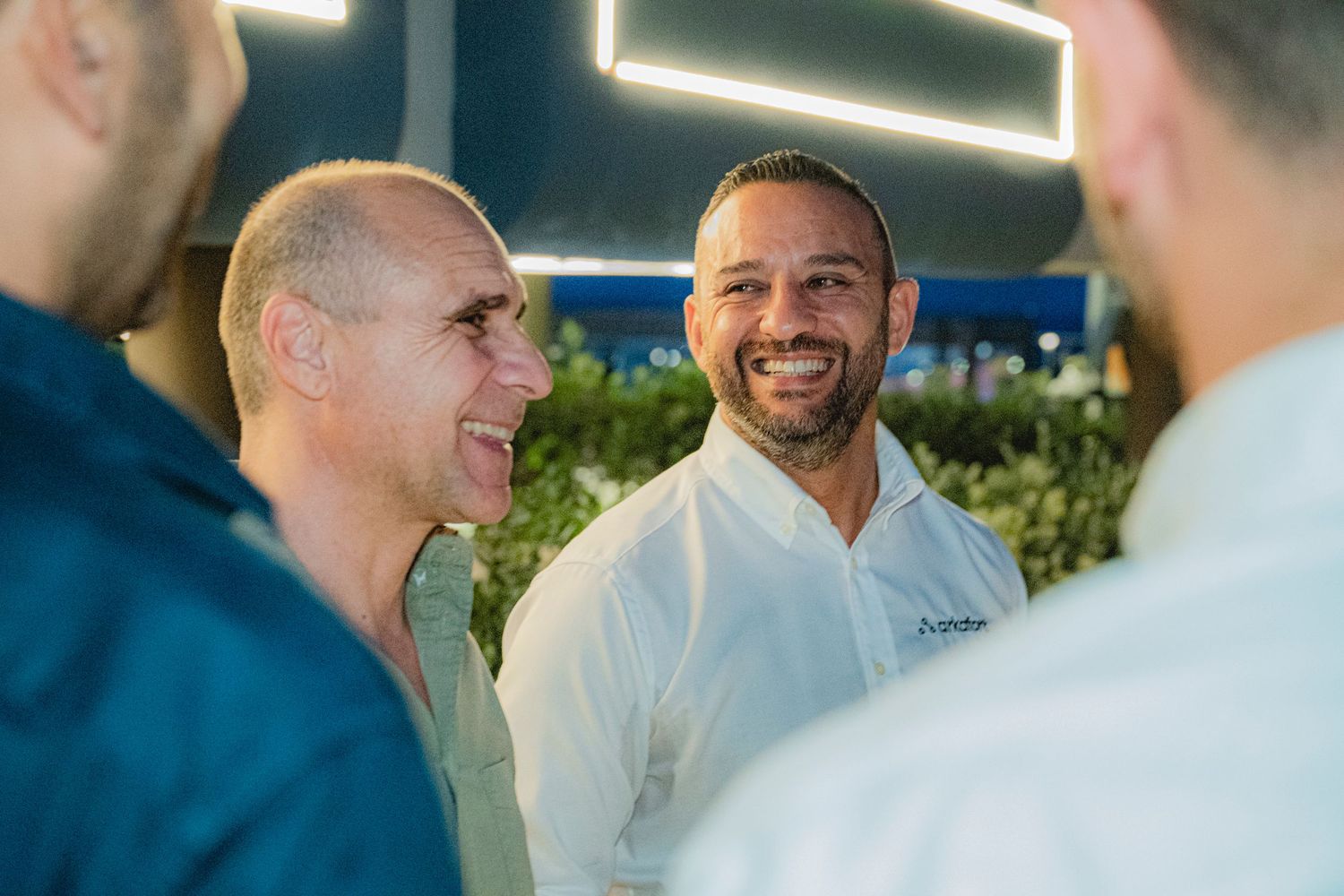 Two men engaged in friendly conversation at an outdoor evening networking event.